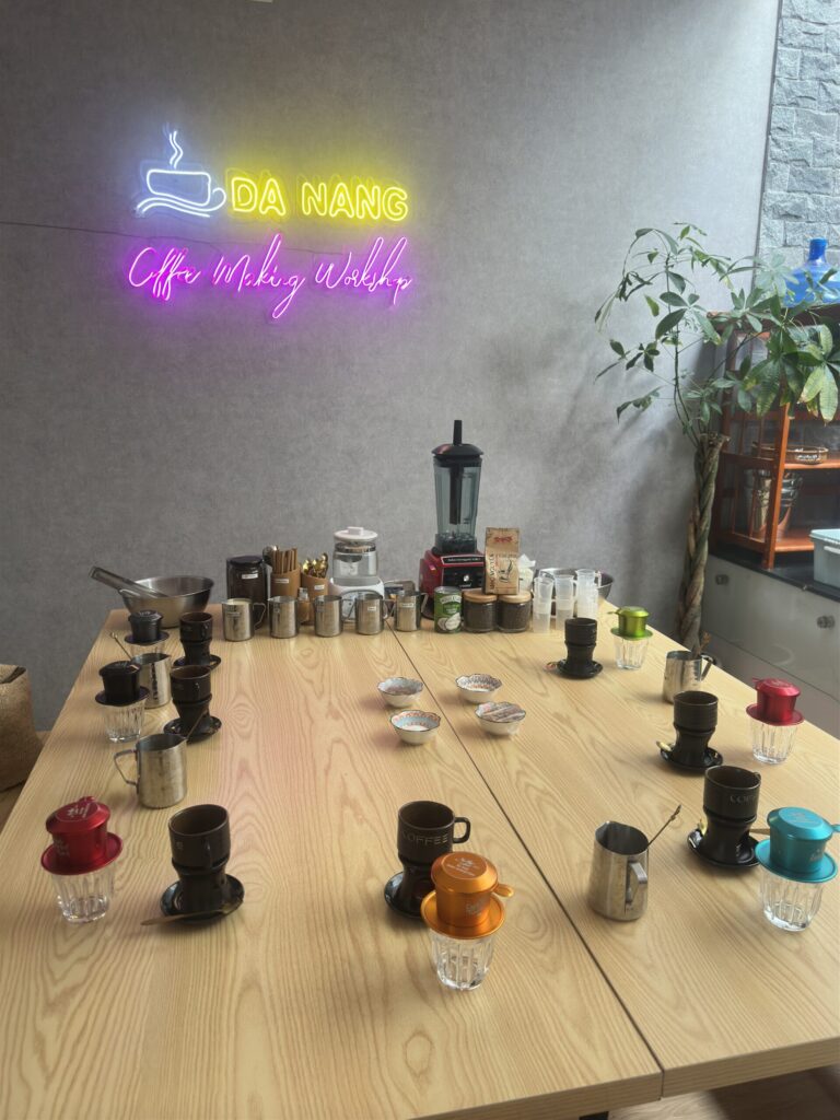 Coffee workshop classroom setup in Da Nang, Vietnam — stainless steel tools, traditional filters, and ingredients lined up on the table.