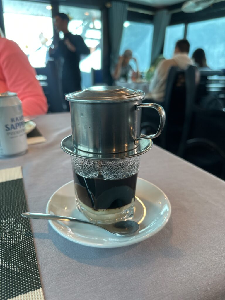 Vietnamese coffee brewing in a traditional phin filter above a glass.