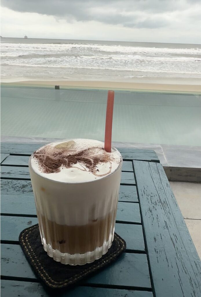 Salt coffee in a glass cup on a table with an ocean view in Da Nang, Vietnam.